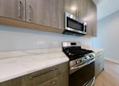 Thumbnail 4 of 61 - A modern kitchen with a stove, microwave, and oak cabinets.