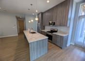 Thumbnail 3 of 61 - A modern kitchen with a marble island and wooden cabinets.
