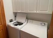 Thumbnail 13 of 13 - A white washing machine and dryer in a small laundry room.