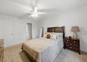 Thumbnail 18 of 37 - A bedroom with a bed, dresser, and ceiling fan.