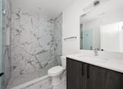 Thumbnail 15 of 27 - A white toilet sits in a bathroom with a marble wall.