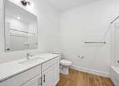 Thumbnail 51 of 60 - A white bathroom with a toilet, sink, and mirror.