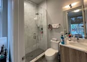 Thumbnail 18 of 45 - A bathroom with a white toilet, a sink, and a shower with a glass door.