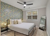 Thumbnail 21 of 31 - A bedroom with a bed, a fan, and a floral wallpaper.