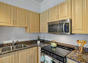 Thumbnail 20 of 46 - A kitchen with wooden cabinets and a black stove top.