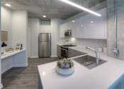 Thumbnail 11 of 31 - A modern kitchen with a stainless steel refrigerator and a white countertop.