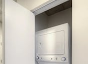 Thumbnail 20 of 31 - A white dryer is in a small space next to a white door.