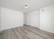 Thumbnail 18 of 27 - A room with a white ceiling and wooden flooring with two white doors.