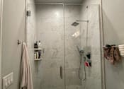 Thumbnail 19 of 45 - A bathroom with a marble wall and a glass shower door.