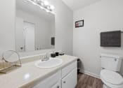Thumbnail 23 of 37 - A white bathroom with a toilet, sink, and mirror.