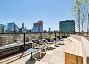 Thumbnail 75 of 84 - A rooftop patio with chairs and tables overlooking a city skyline.