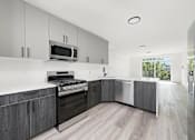 Thumbnail 2 of 27 - A modern kitchen with a stove top oven and microwave.