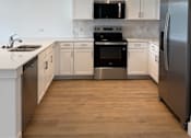 Thumbnail 14 of 24 - A modern kitchen with white cabinets and stainless steel appliances.