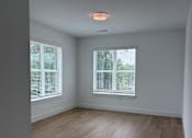 Thumbnail 16 of 24 - A room with wooden flooring and two windows with blinds.