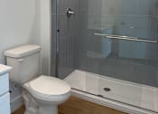 Thumbnail 21 of 24 - A white toilet sits next to a walk-in shower.