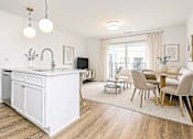 Thumbnail 2 of 9 - A kitchen with a white island and a dining table with chairs.