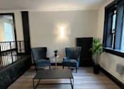 Thumbnail 15 of 18 - A living room with a black coffee table and two blue chairs.