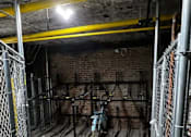 Thumbnail 18 of 18 - A large, empty warehouse with a brick wall and a yellow pipe.