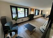 Thumbnail 14 of 18 - A living room with a black sofa, a grey armchair, a black coffee table, and a white couch.