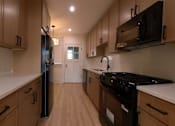 Thumbnail 1 of 13 - A kitchen with wooden cabinets and black appliances.