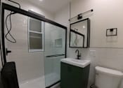 Thumbnail 11 of 13 - A white toilet sits next to a sink in a bathroom.