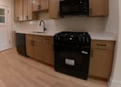 Thumbnail 4 of 13 - A kitchen with black appliances and wooden cabinets.