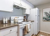 Thumbnail 21 of 48 - A kitchen with white appliances and a painting on the wall.