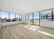 Thumbnail 16 of 54 - A room with a wooden floor and large windows overlooking a cityscape.