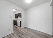 Thumbnail 26 of 37 - A kitchen with white walls and a wooden floor.