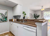 Thumbnail 22 of 48 - A kitchen with white cabinets and a brown countertop.