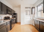 Thumbnail 11 of 21 - a kitchen with stainless steel appliances and black cabinets and a white door