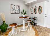 Thumbnail 23 of 48 - A green vase sits on a white table in a room with a white wall and a painting hanging on it.