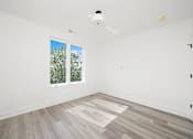 Thumbnail 24 of 27 - A room with a window and wooden flooring.
