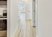 Thumbnail 23 of 54 - A long hallway with white walls and wood flooring.