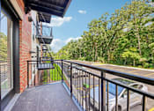 Thumbnail 59 of 60 - A balcony with a black railing and a view of a parking lot and trees.