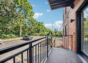 Thumbnail 60 of 60 - A black metal railing on a wooden deck overlooks a parking lot.