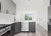 Thumbnail 3 of 27 - A modern kitchen with a stove, sink, and refrigerator.