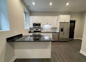 Thumbnail 3 of 20 - A modern kitchen with a black countertop and stainless steel appliances.