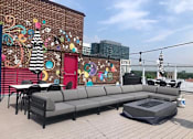 Thumbnail 52 of 54 - A patio with a grey sofa and a table with a black tablecloth on it.
