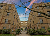 Thumbnail 2 of 15 - a courtyard between two brick buildings with a blue sky
