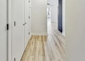 Thumbnail 46 of 54 - A long hallway with white walls and wood flooring.