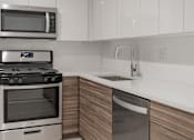 Thumbnail 4 of 16 - A modern kitchen with a stainless steel dishwasher and microwave above the stove.