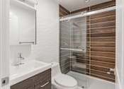 Thumbnail 6 of 16 - A modern bathroom with a walk-in shower and a white sink.