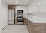 Thumbnail 2 of 16 - A modern kitchen with a refrigerator, microwave, oven, and sink.