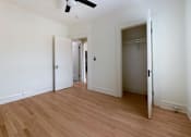 Thumbnail 12 of 13 - A room with a ceiling fan and wooden flooring.