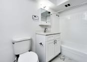 Thumbnail 47 of 54 - A white toilet sits next to a white cabinet with a mirror above it.