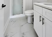 Thumbnail 40 of 54 - A white toilet in a bathroom with a walk-in shower.