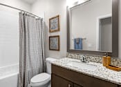 Thumbnail 12 of 37 - A bathroom with a toilet, sink, and shower curtain.