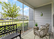 Thumbnail 14 of 37 - A balcony with a bench, chair, and potted plant.