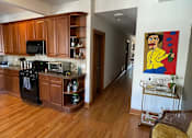 Thumbnail 4 of 13 - A kitchen with wooden cabinets and a painting on the wall.